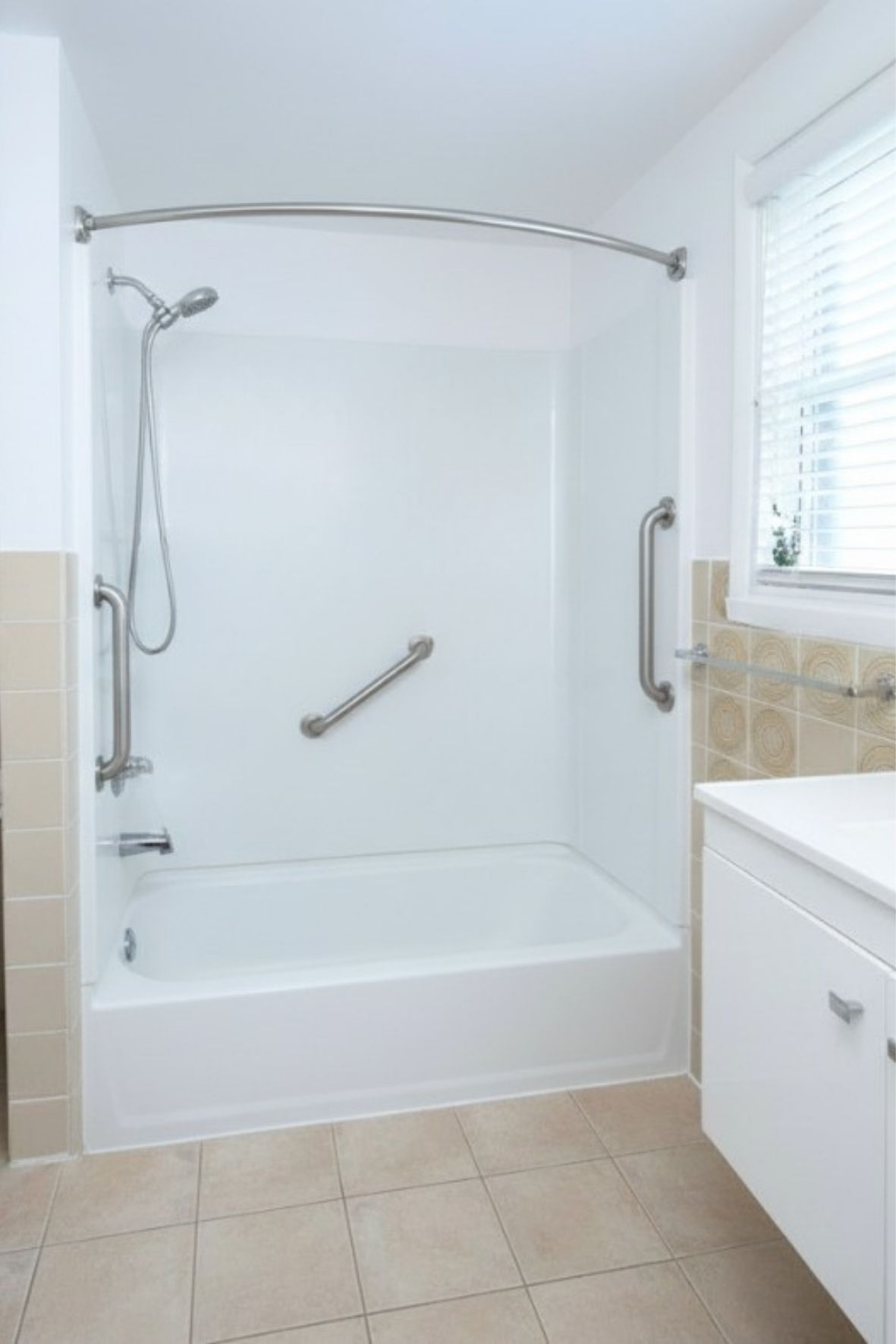 baignoire avec barres d’appui et douche intégrée dans une salle de bain fonctionnelle  à Montmagny